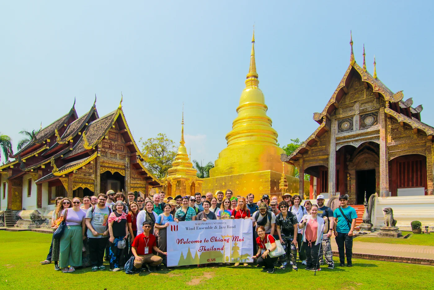 Travel group visiting a Thai temple with a golden pagoda and ornate architecture