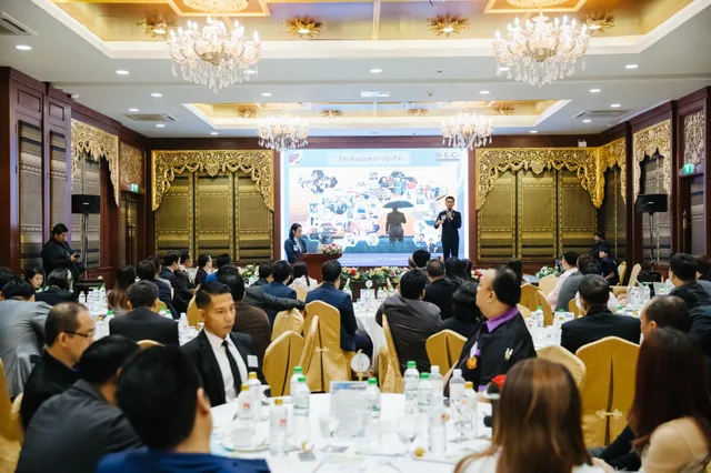 An audience watching Phudit present at the front of a conference room