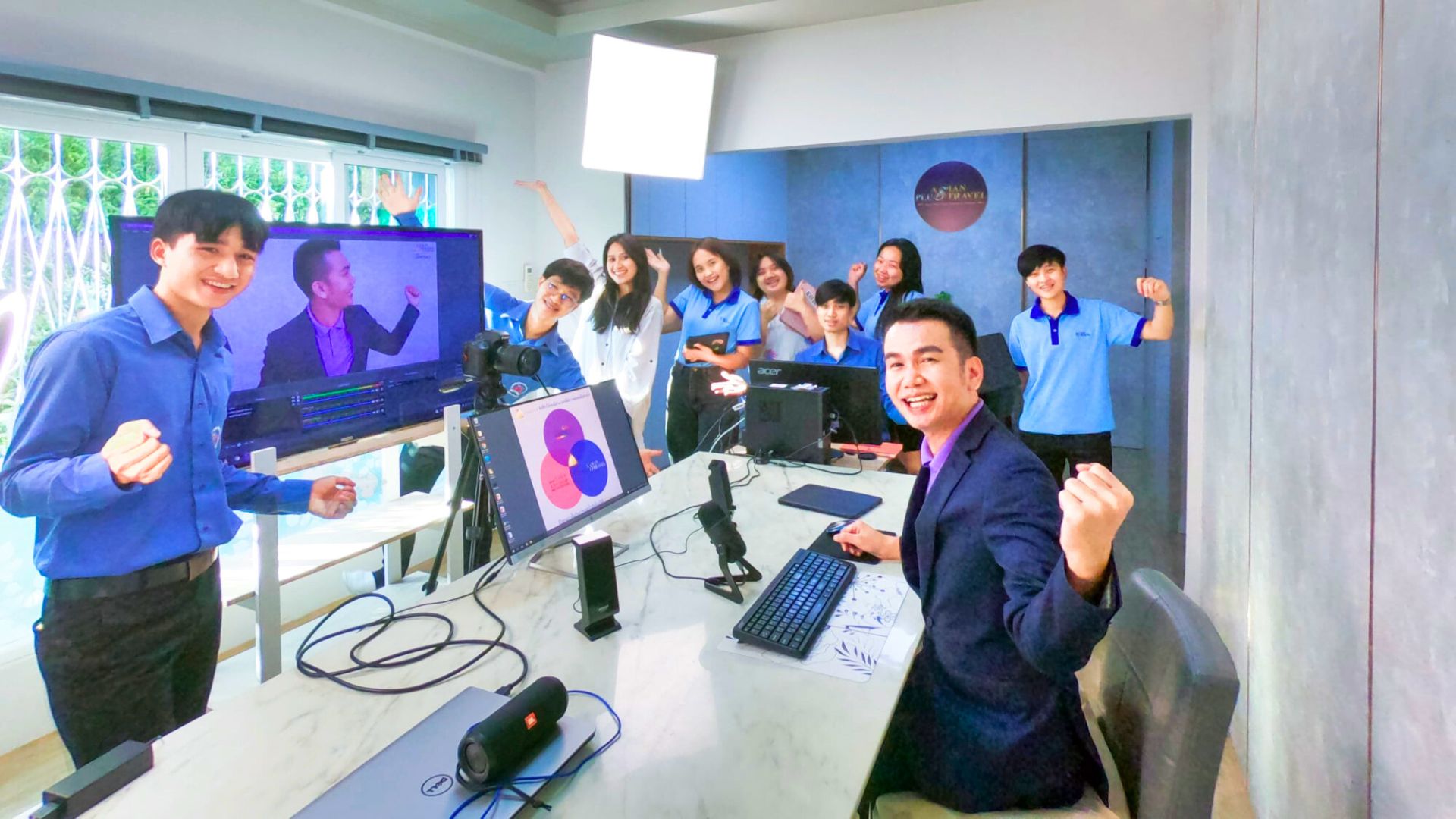 Team members gathered around computers and a camera in the office