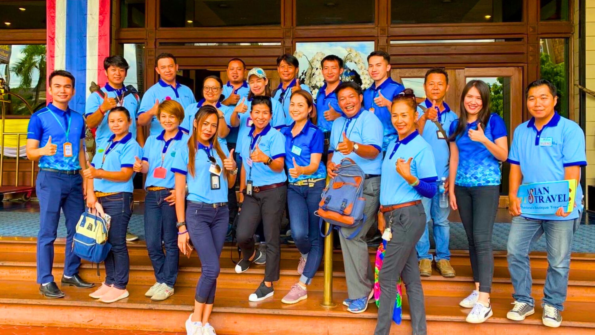 Team members in blue shirts gathered on the steps of a building
